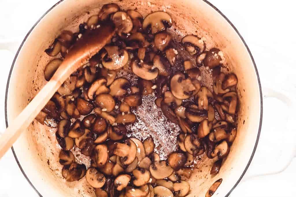 Mushrooms cooking browning in the bottom of the pan