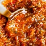 a jar of red pesto with a spoon in it