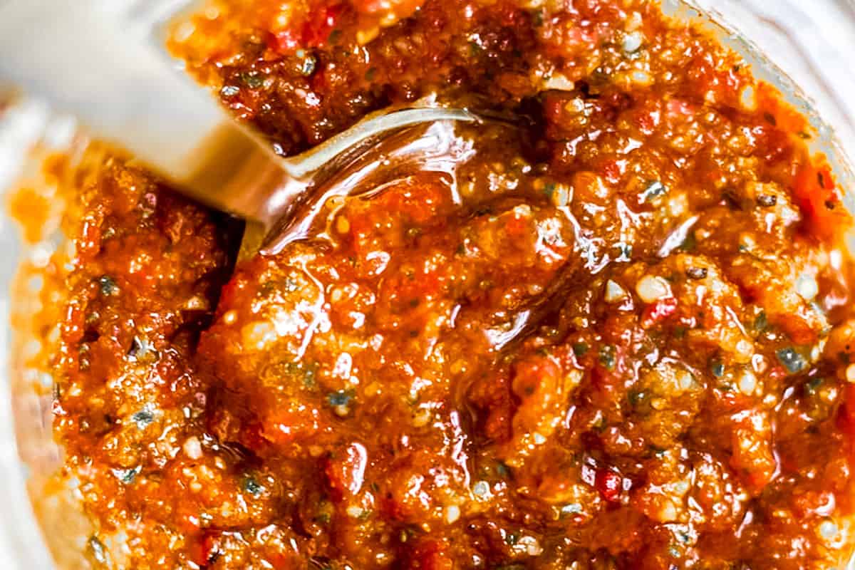 a jar of red pesto with a spoon in it