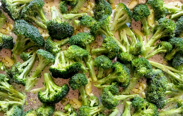 The broccoli on a baking tray coated in olive oil with garlic, and salt and pepper.