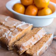 a tangerine drizzle cake sliced with a bowl of tangerines in the background