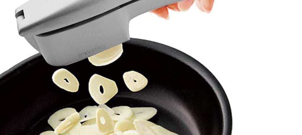 a gaget pressing sliced garlic through a garlic press