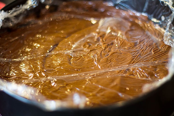 The filling added to the pan covered with plastic wrap that is touching the filling