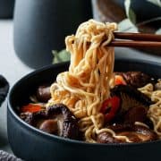 Chinese Mushroom Noodle Soup in a bowl with noodles on chopsticks.