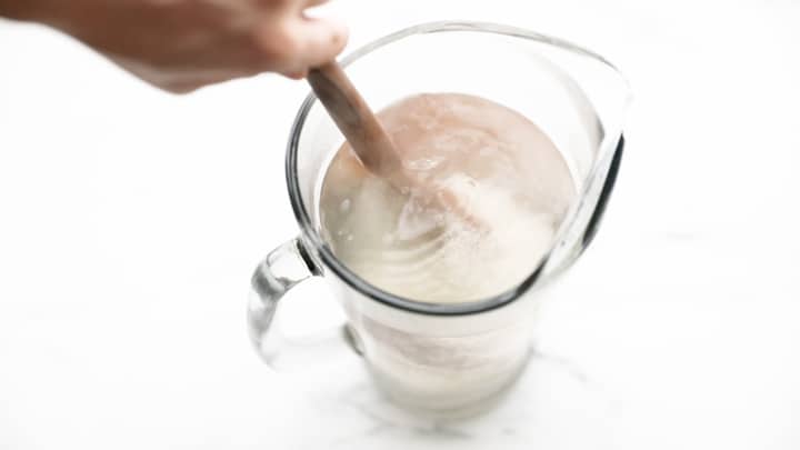 Sugar being stirred in a pitcher of hot water