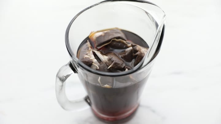 Tea bags steeping in a pitcher of hot water