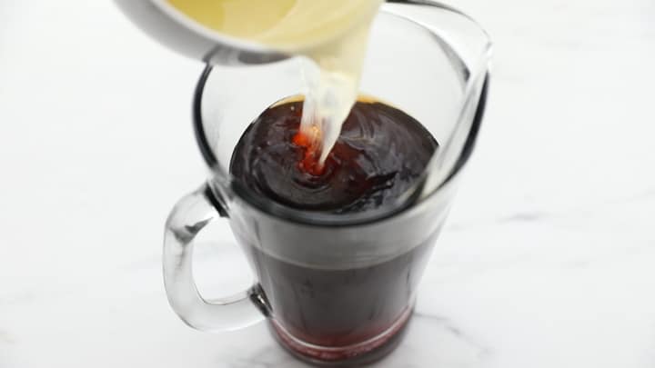 Lemon juice pouring into a pitcher of tea