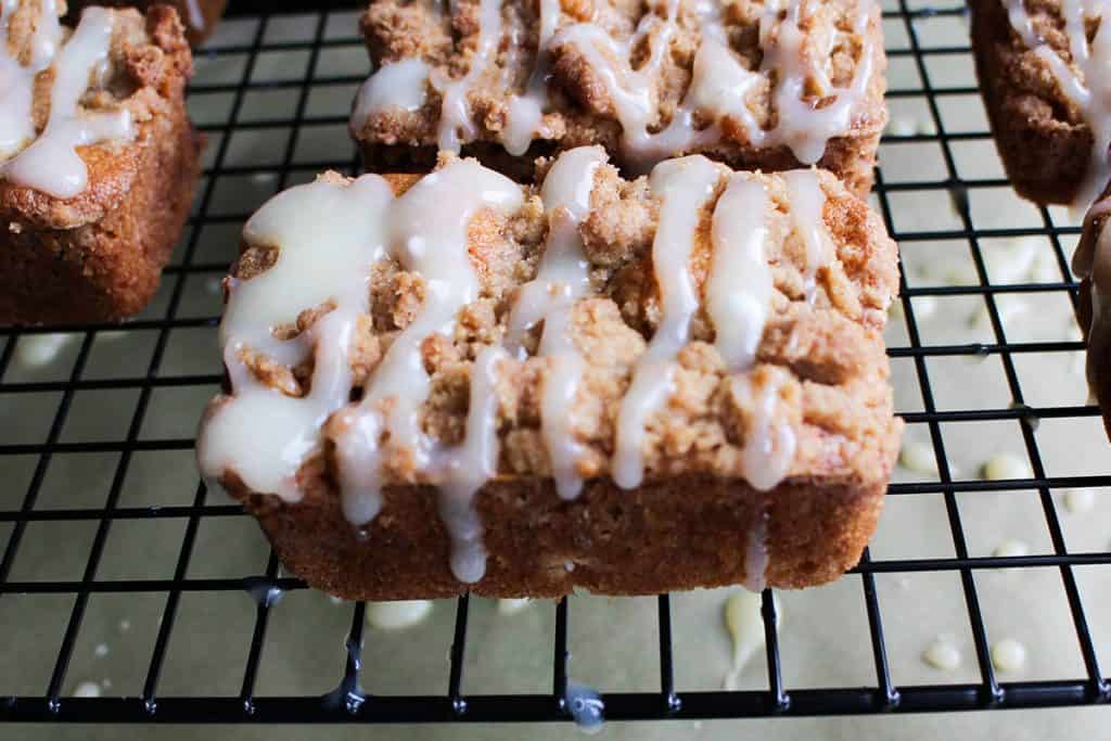 Apple Crumb Cakes on a rack drizzled with icing.