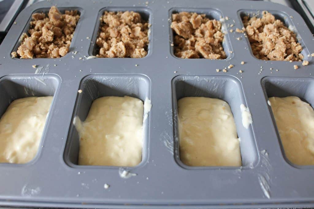 apple crumb cake batter in a mini loaf pan, half with topping, half without