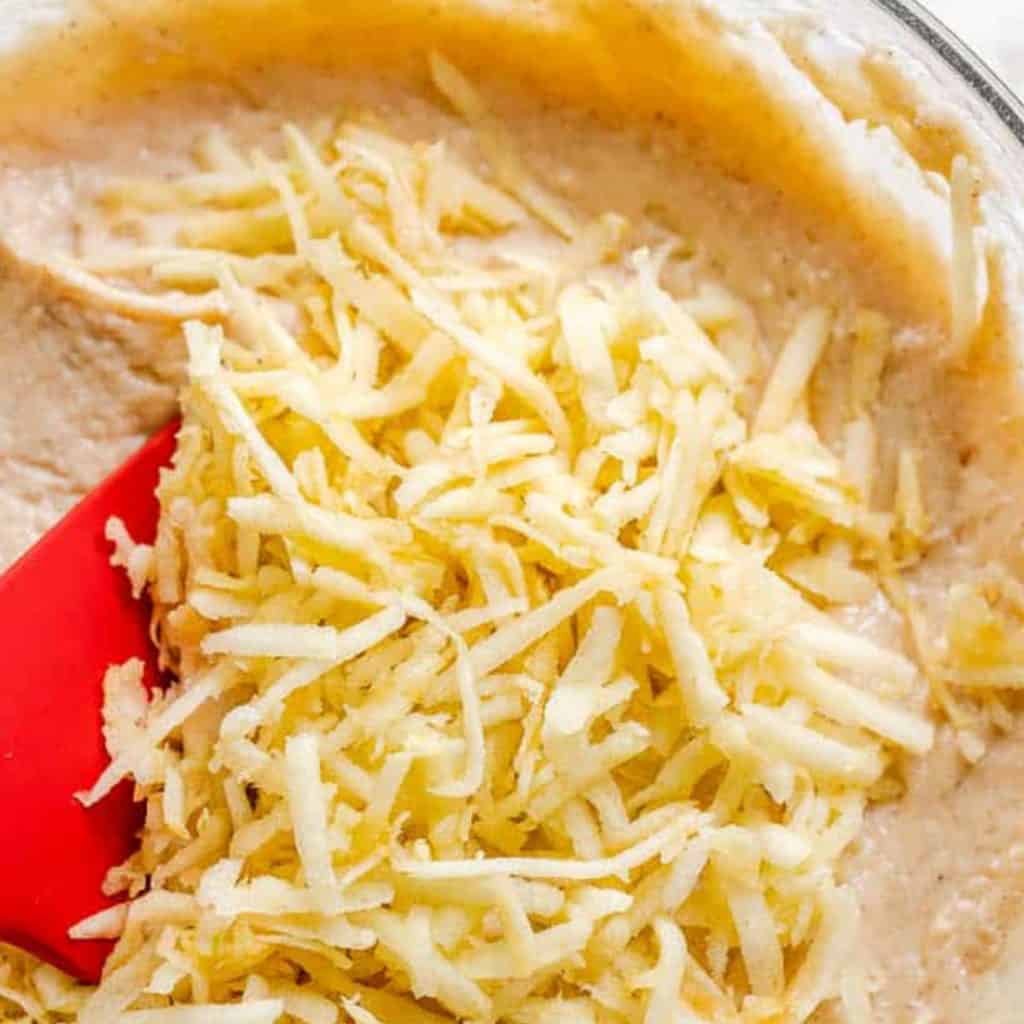 shredded apple on top of batter in a glass mixing bowl