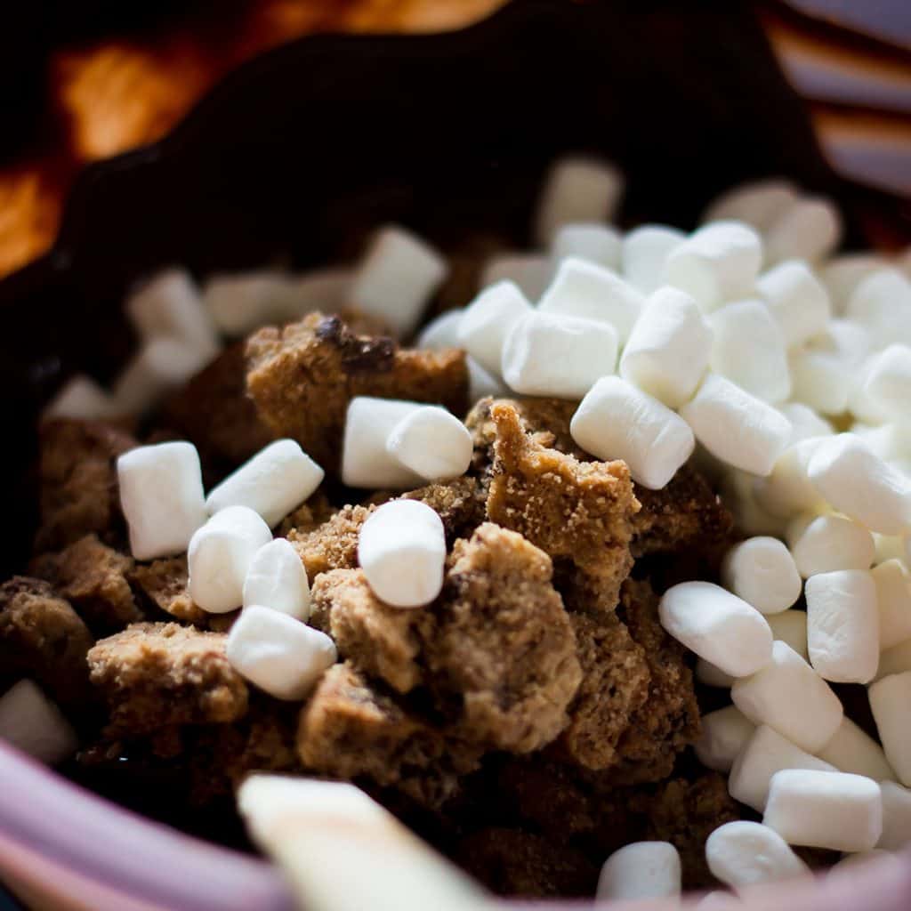 melted chocolate, mini marshmallows, and cookie pieces in a bowl