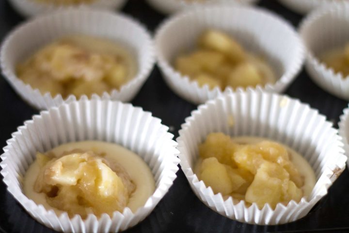Apple Cheesecake Muffins batter in a pan with the apple mixture on top, ready to bake