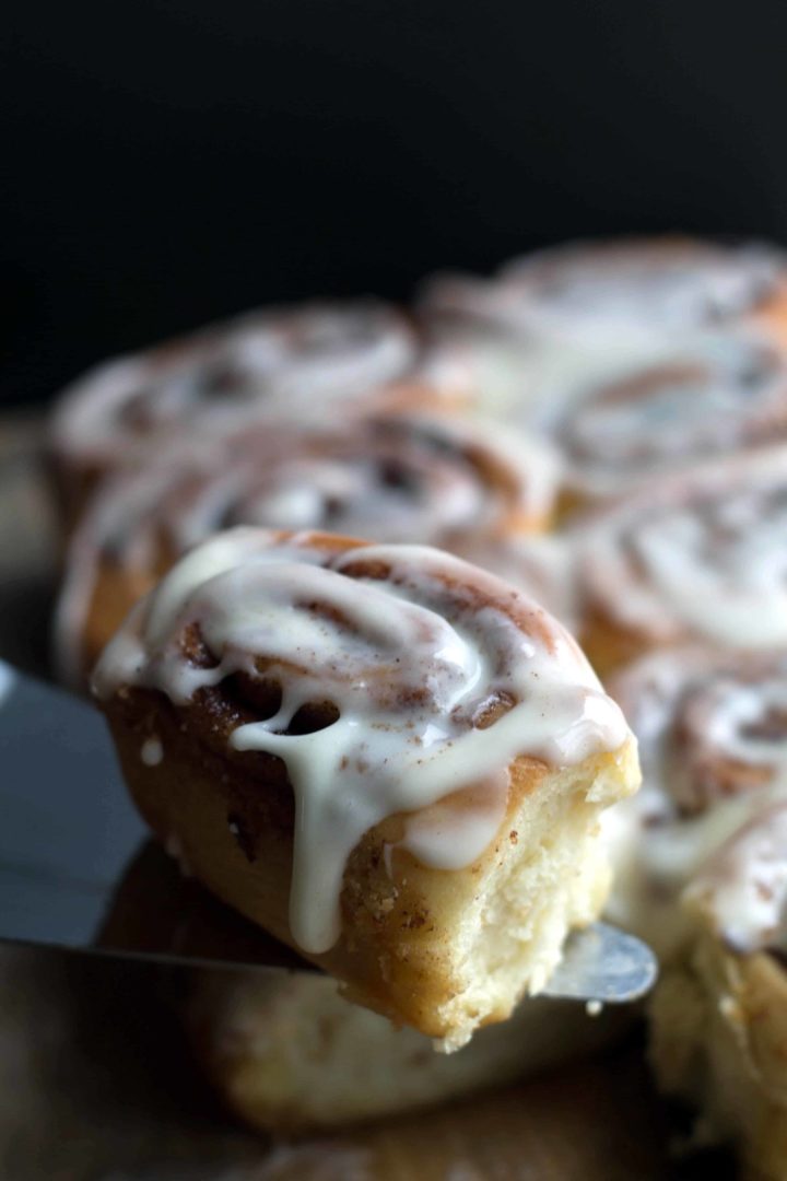 Easy Cinnamon Roll on a serving slice with the rest of the batch in the background