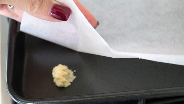 A bit of dough in the corner of the pan with the baking paper being placed over it.