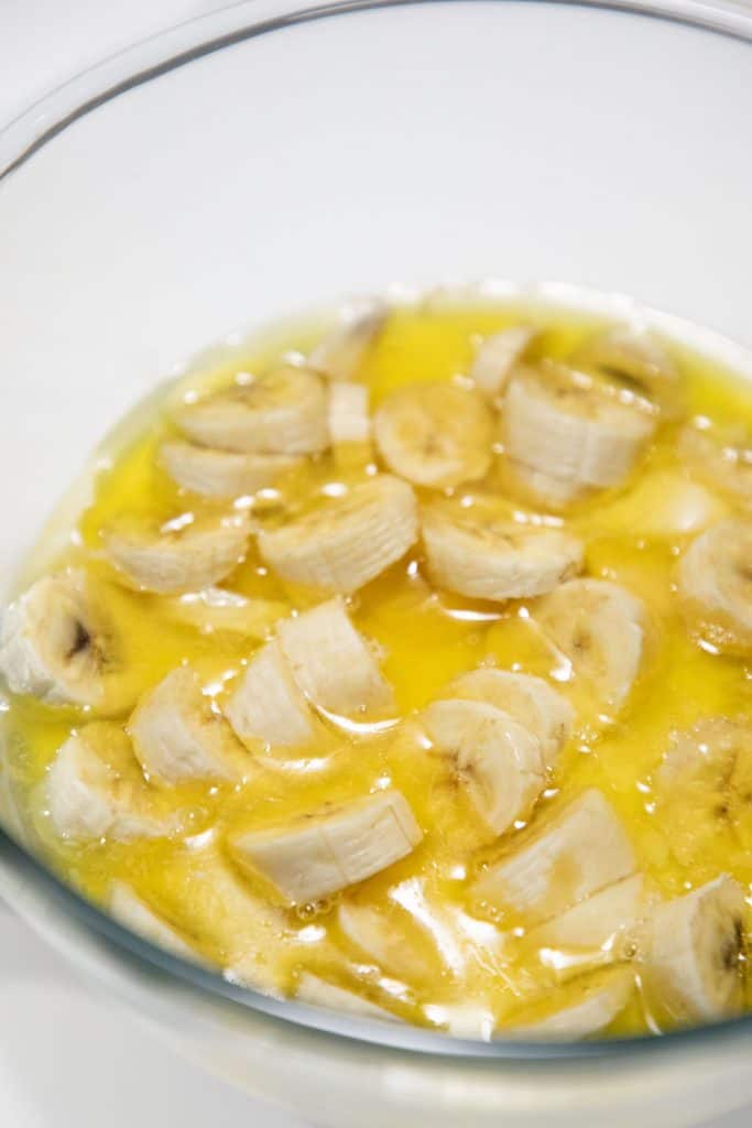 sliced bananas in a bowl with melted butter