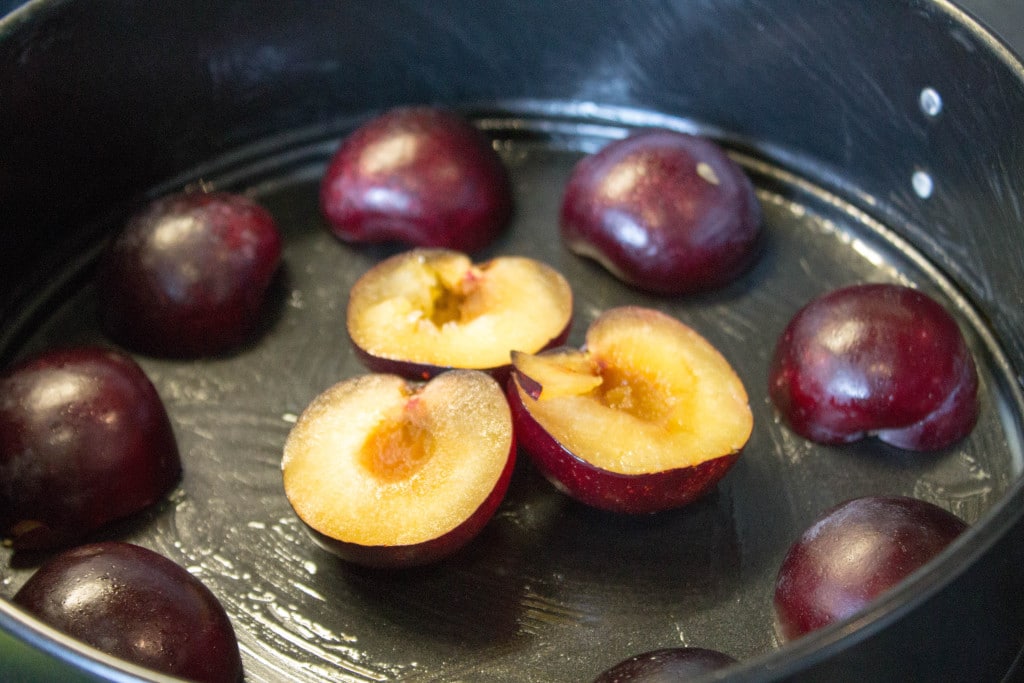 halved plums arranged in a pattern in a pan