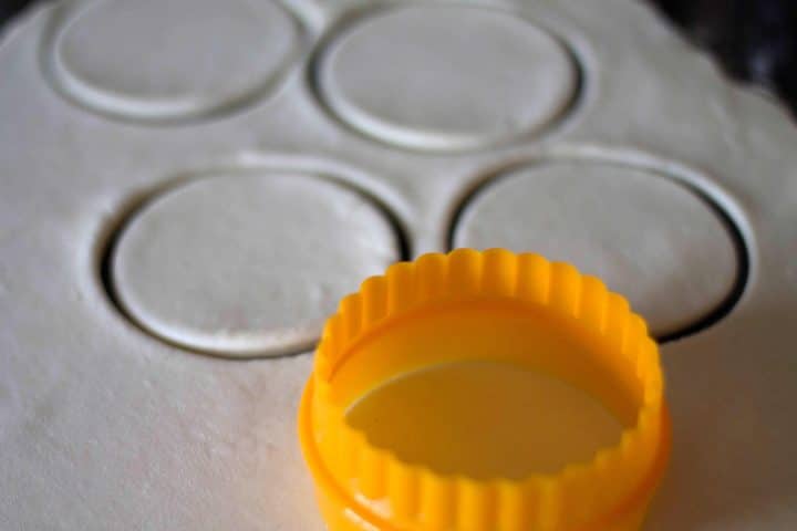 a grey metal cupcake pan with a bright orange cookie cutter