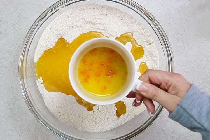 The orange juice and zest being added to the bowl