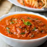 A bowl of Quick & Easy Marinara Sauce topped with fresh basil