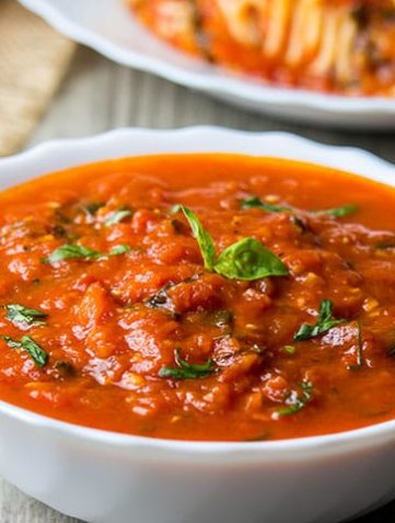 A bowl of Quick & Easy Marinara Sauce topped with fresh basil
