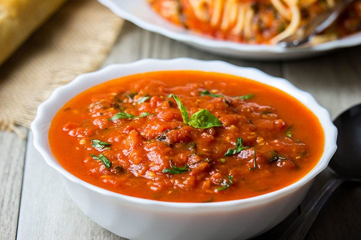 A bowl of Quick & Easy Marinara Sauce topped with fresh basil