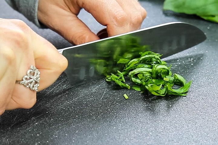 The rolled basil being sliced into thin slices