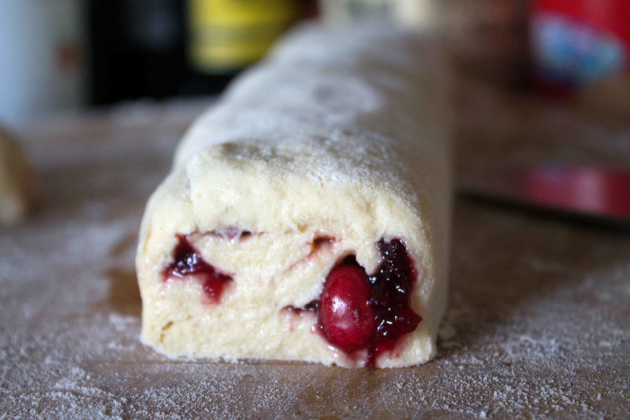 scone dough rolled into a sausage shape with a cross section showing the cranberries inside