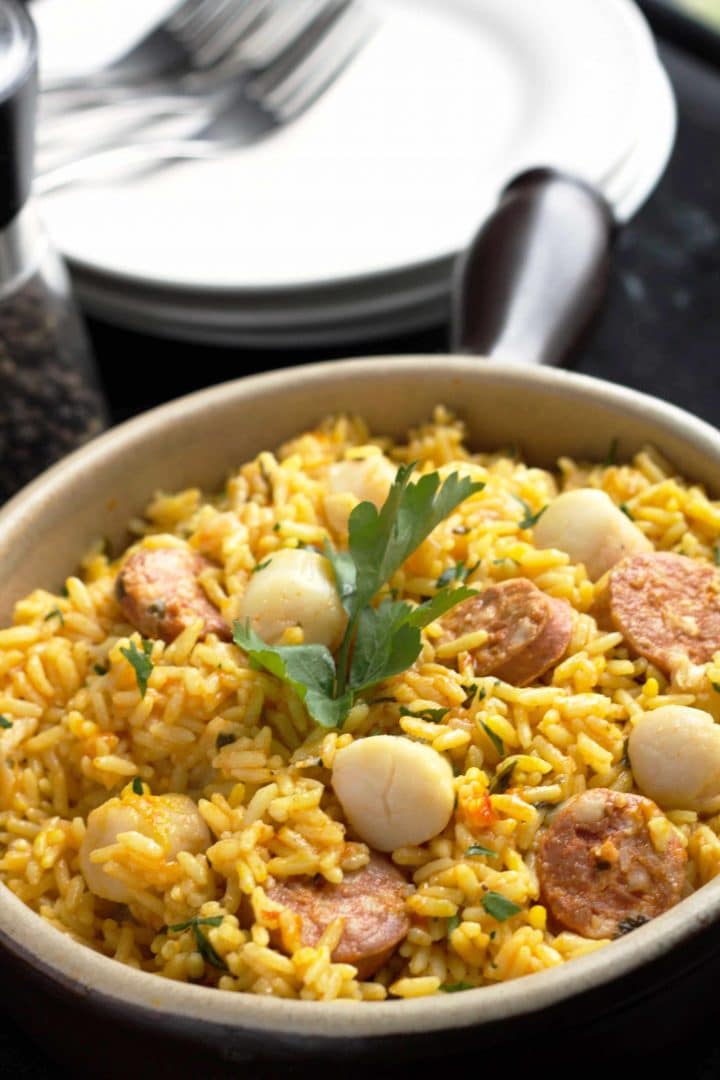 Easy Scallops & Chorizo Paella in a pan with dishes and forks on the table in the background