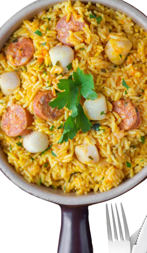 Over head shot of a dish of yellow rice with scallops and chorizo