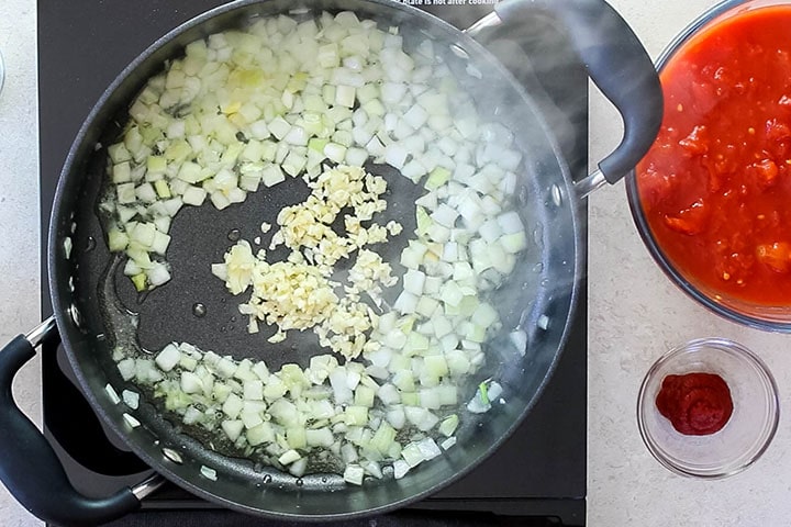 A pan with onions and garlic cooking in olive oil