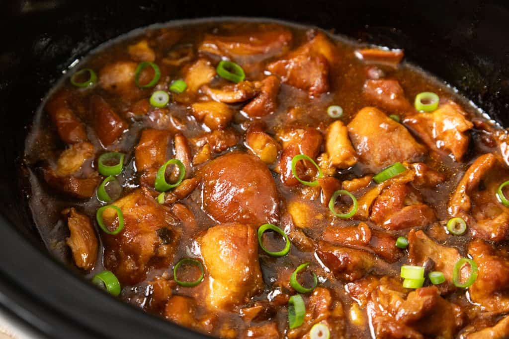 Chunks of glazed chicken in a rich brown sauce, garnished with sliced green onions, simmering in a slow cooker—this Slow Cooker Honey Soy Chicken is perfect for an easy, flavorful meal.