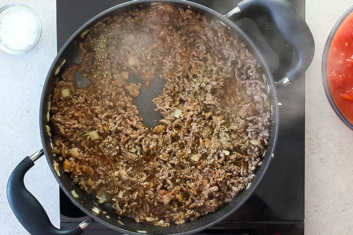 A pan with the oregano added to the ground beef