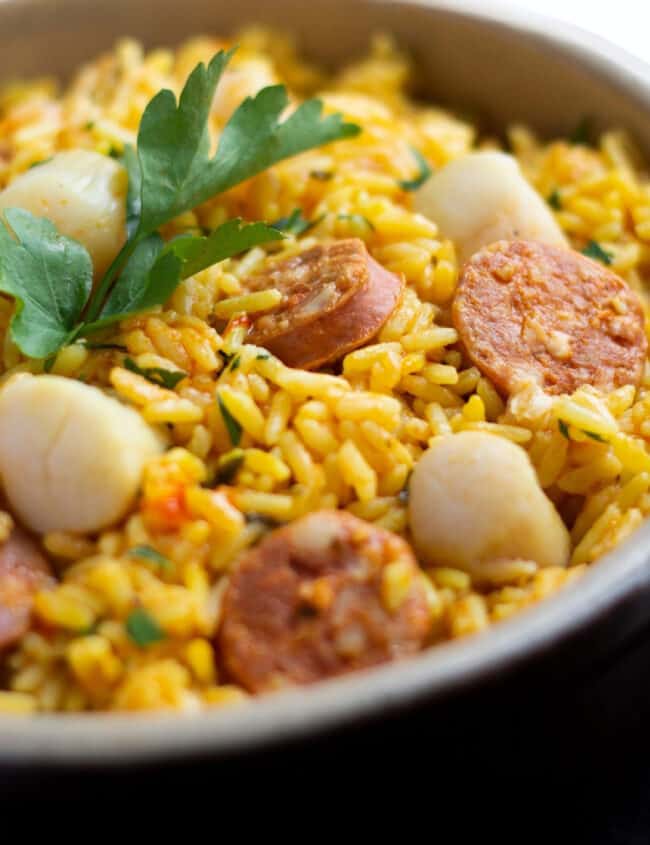 a dish of yellow rice with scallops and chorizo