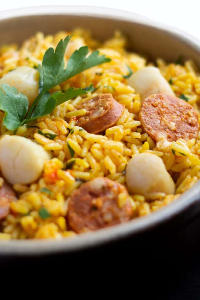 a dish of yellow rice with scallops and chorizo