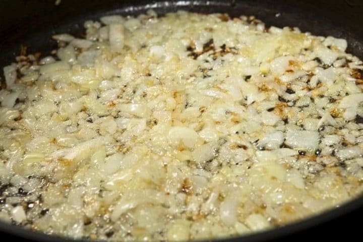 A pan with onions and garlic cooking in olive oil
