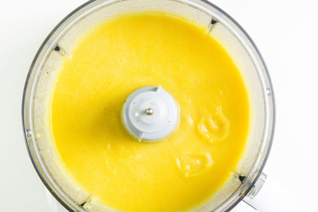 A food processor bowl filled with smooth, bright yellow blended mixture, viewed from above&mdash;perfect for making Low Fat Creamy Cauliflower Saffron Soup.