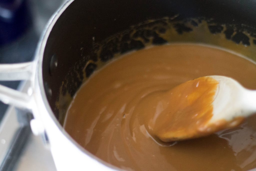 Caramel being stirred in a pot with a wooden spoon