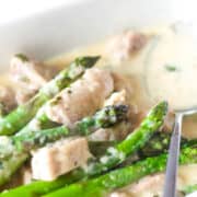 a pan of chicken and asparagus in a cream sauce