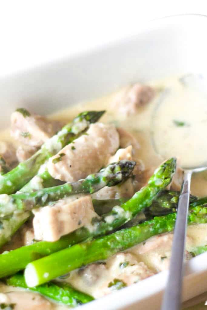 a pan of chicken and asparagus in a cream sauce