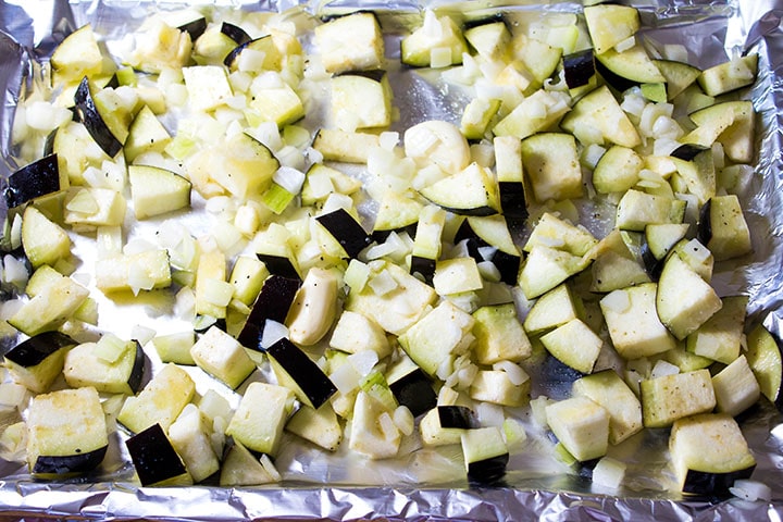 The cubed eggplant and onions on a pan ready to roast