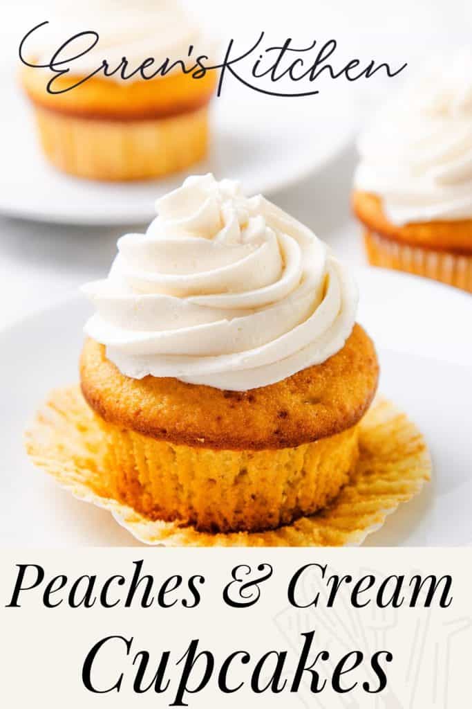 A cupcake with swirled cream frosting on a white plate, with another Peaches and Cream Cupcake blurred in the background. Text reads: “Erren’s Kitchen Peaches & Cream Cupcakes.”.
