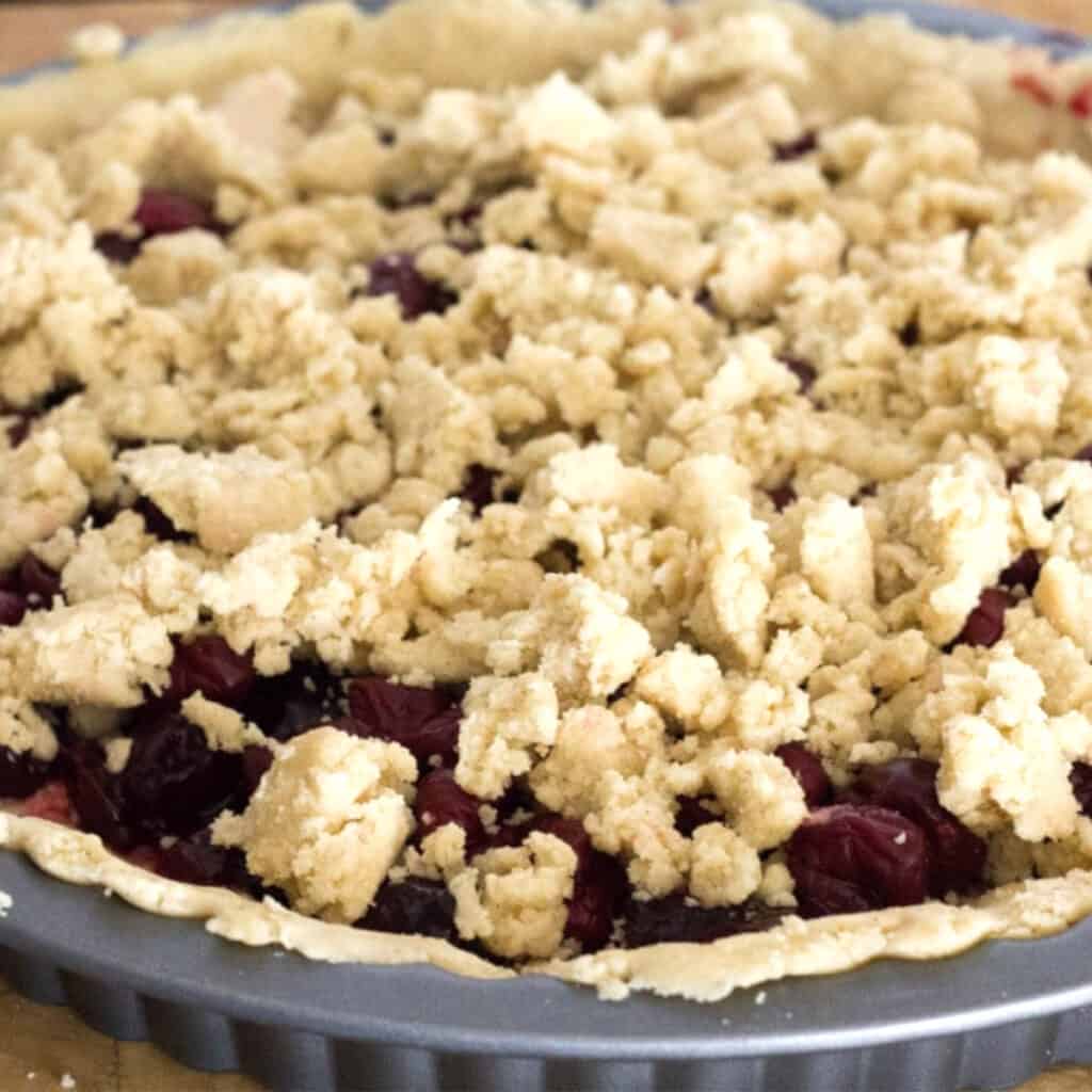 jam and cherries in a pie shell covered woth crumbled dough
