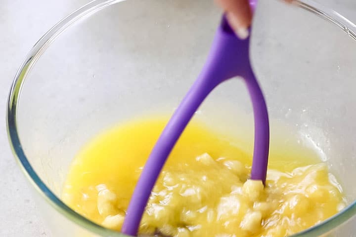 a potato masher mashing the bananas