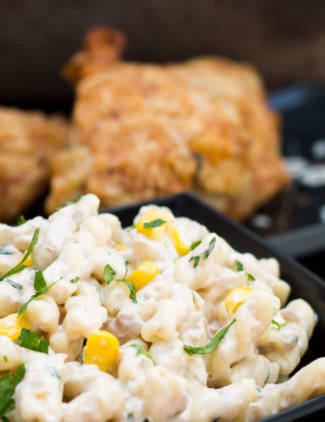 Quick and Easy Corn & Tuna Pasta Salad in a black bowl with chicken in the background