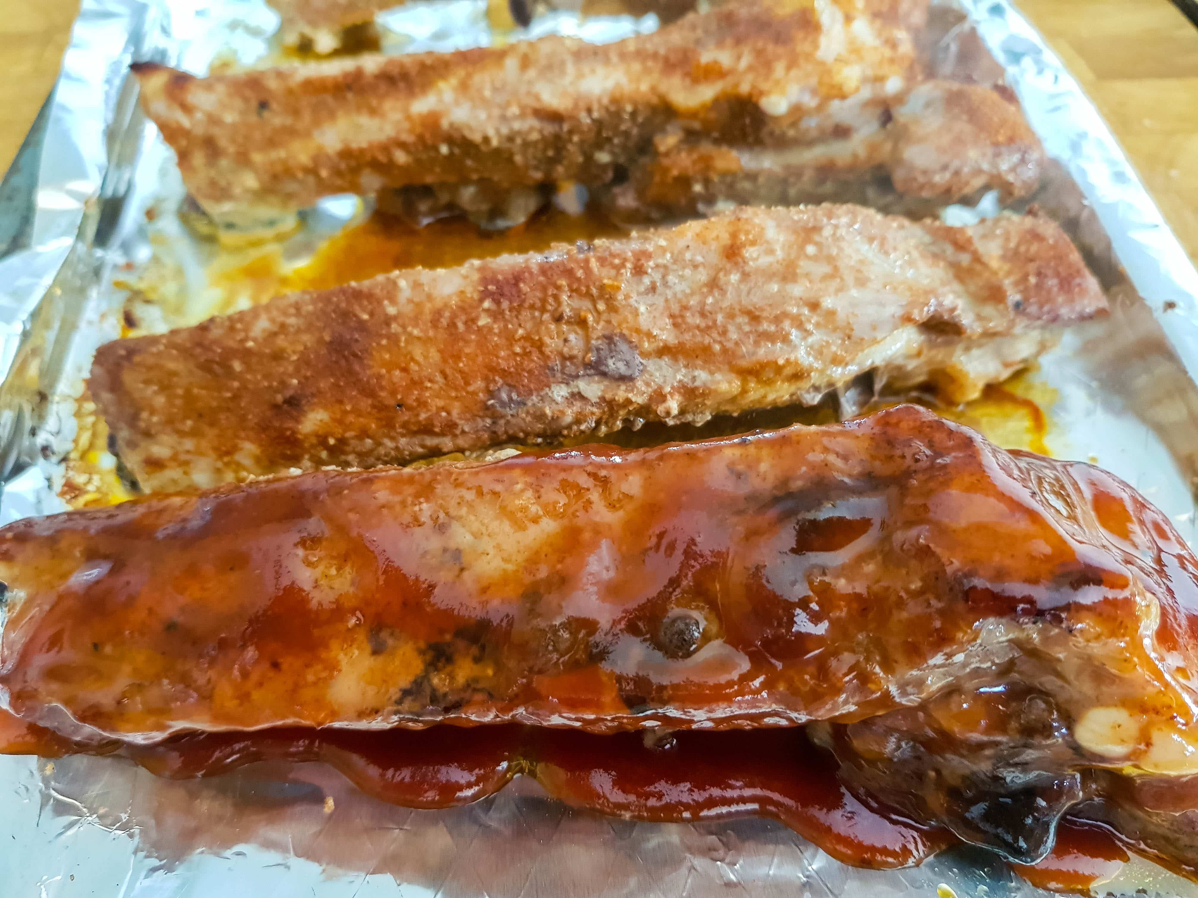 Barbecued sticky glazed ribs on a pan with sauce