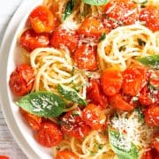 spaghetti with roasted cherry tomato and fresh basil in a white plate