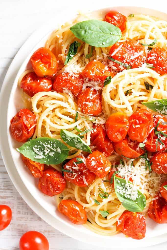 spaghetti with roasted cherry tomato and fresh basil in a white plate