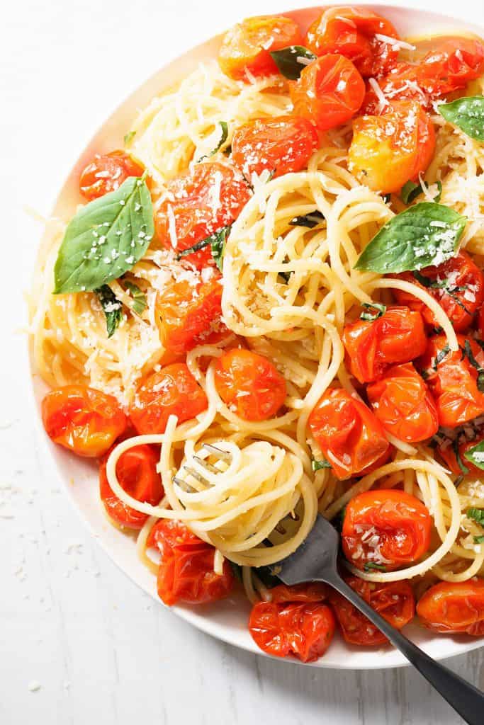 spaghetti with roasted cherry tomato and fresh basil in a white plate