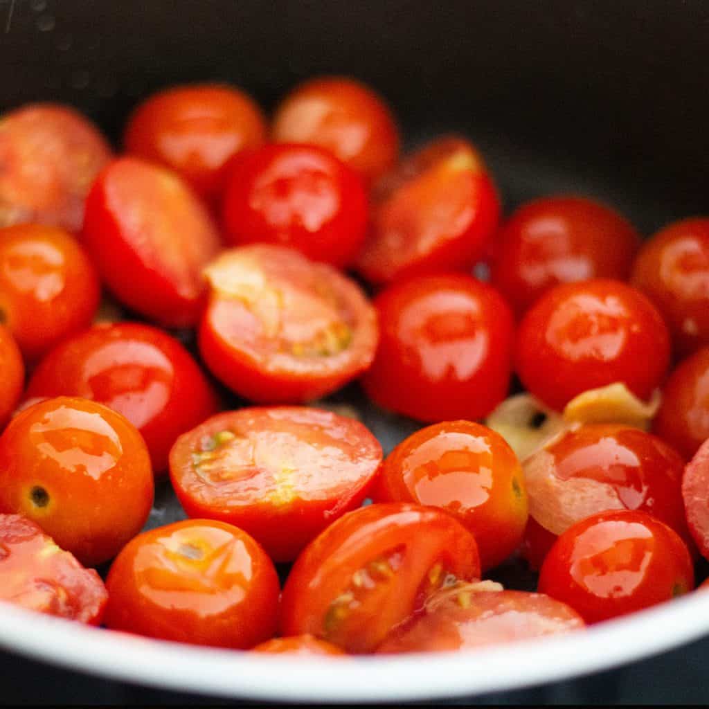 cherry tomatoes added to the pan with the garlic