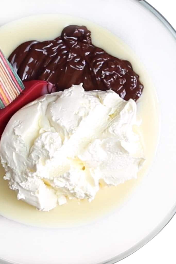 condensed milk, melted chocolate and whipped cream in a mixing bowl.